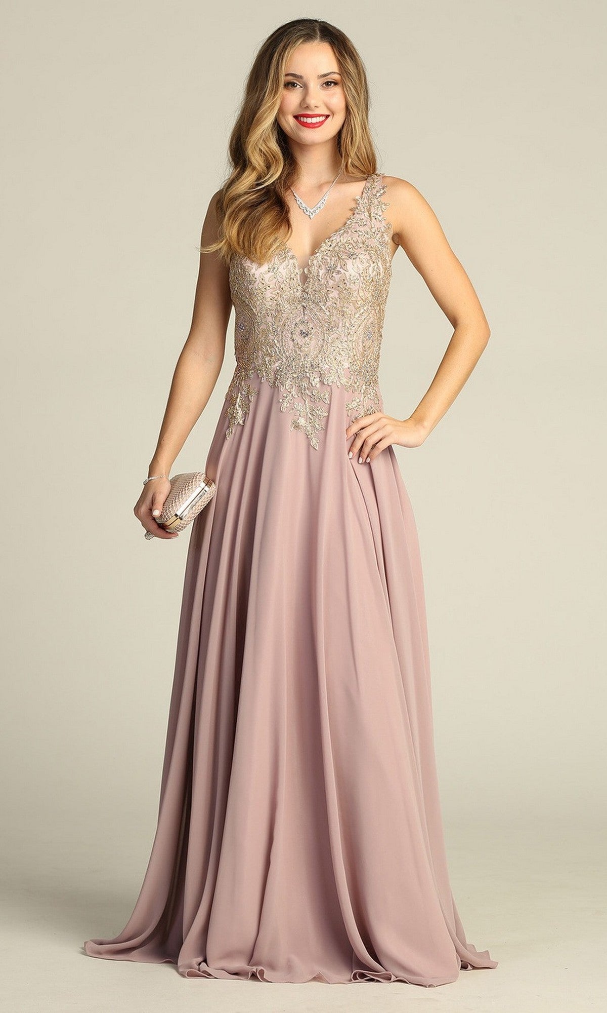A woman wearing the Long Formal Dress: Chicas DM4006 in mocha, featuring a sleeveless design with an embroidered bodice and a flowing chiffon A-line skirt with silver embellishments, accessorized with a necklace, bracelet, and holding a small clutch.